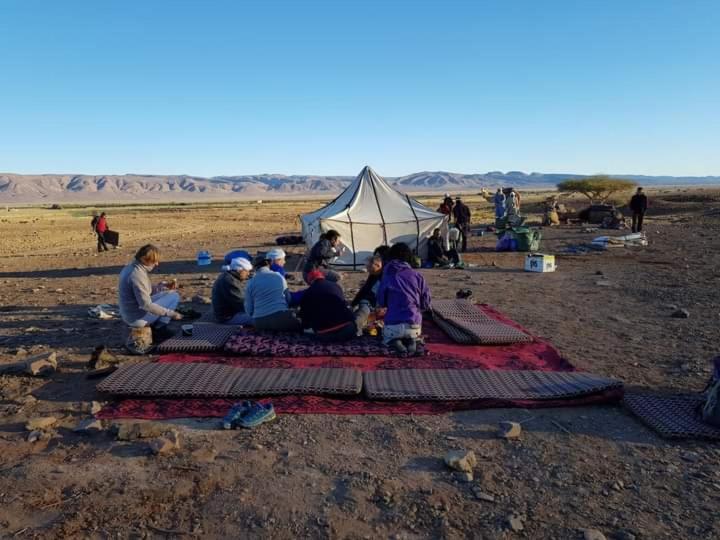 um grupo de pessoas sentadas em torno de uma tenda no deserto em GITE Take Ur time em Merzouga