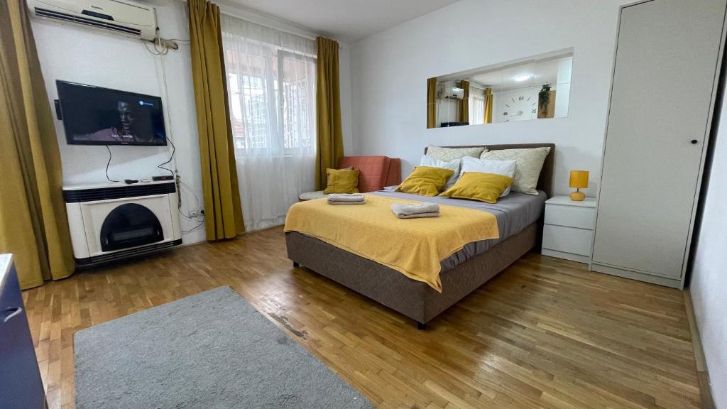 a bedroom with a bed with yellow pillows and a television at Voždovac Vitanovacka in Belgrade