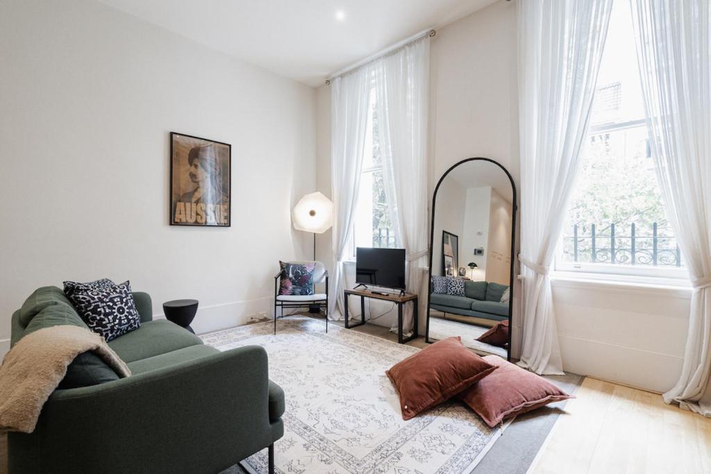 een woonkamer met een groene bank en een spiegel bij StayCentral - Merigold 21 on Collins (CBD) in Melbourne