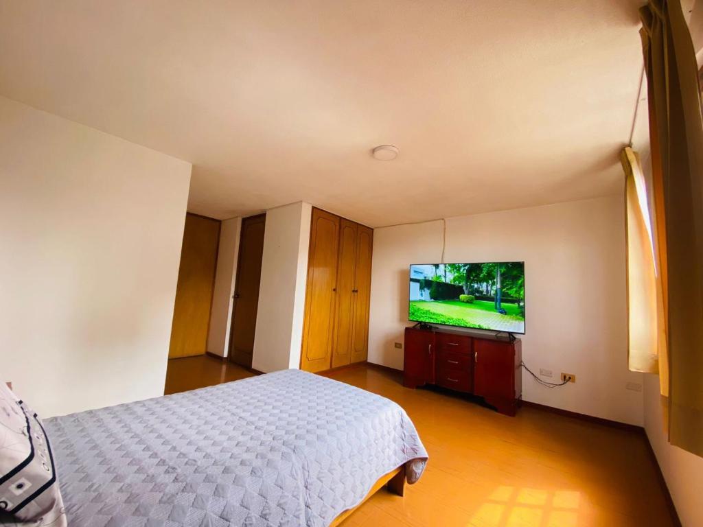 um quarto com uma cama e uma televisão de ecrã plano em Casa Zela em Yanahuara