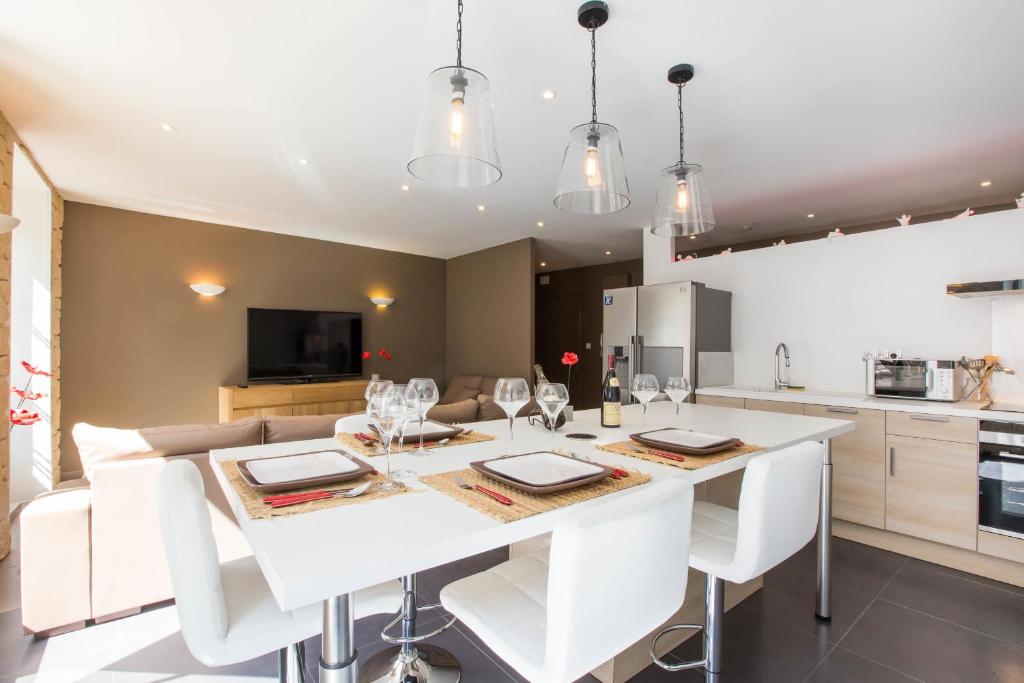 een keuken en eetkamer met een witte tafel en stoelen bij Le Pavean in Beaune