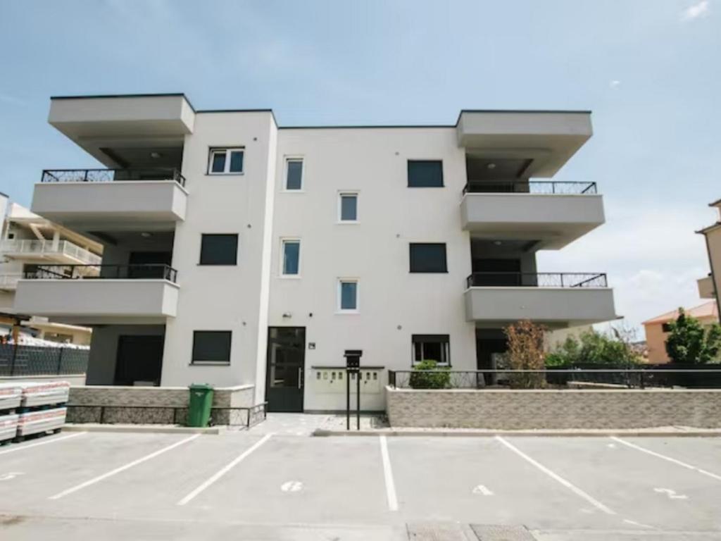 um edifício branco com um parque de estacionamento em frente em Apartments with a parking space Trogir - 22616 em Trogir