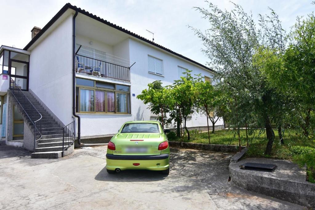 a green car parked in front of a house at Apartments by the sea Umag - 22628 in Umag