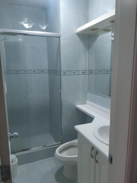 ein weißes Bad mit einer Dusche und einem WC in der Unterkunft Habitación individual Business in Quito