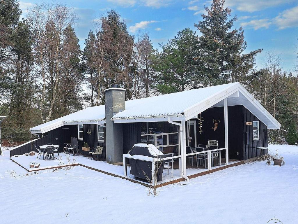 a black house with a snow covered roof in the snow at Holiday home Fjerritslev XIX in Fjerritslev