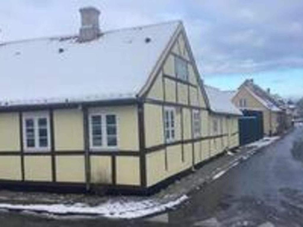 ein Schwarz-Weiß-Gebäude mit Schnee drauf in der Unterkunft Holiday home Nysted VIII in Nysted