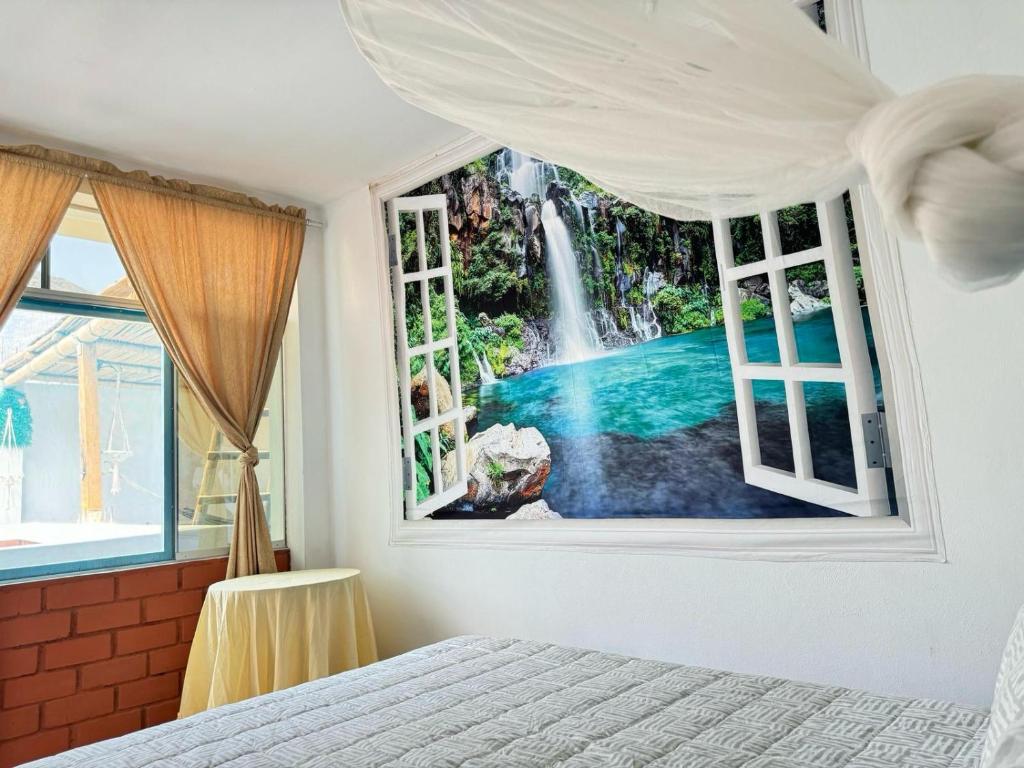 a bedroom with a waterfall seen through a window at Hospedaje Don Lalo in Tortuga