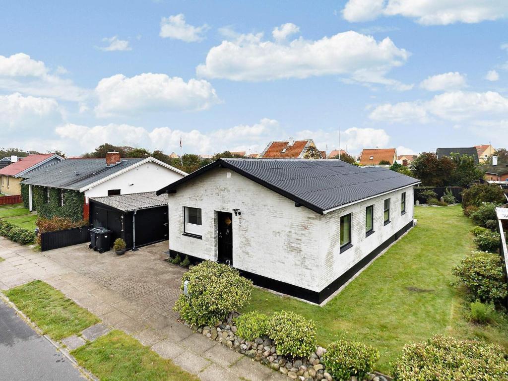 a white house with a black roof on a yard at Holiday home Skagen XL in Skagen