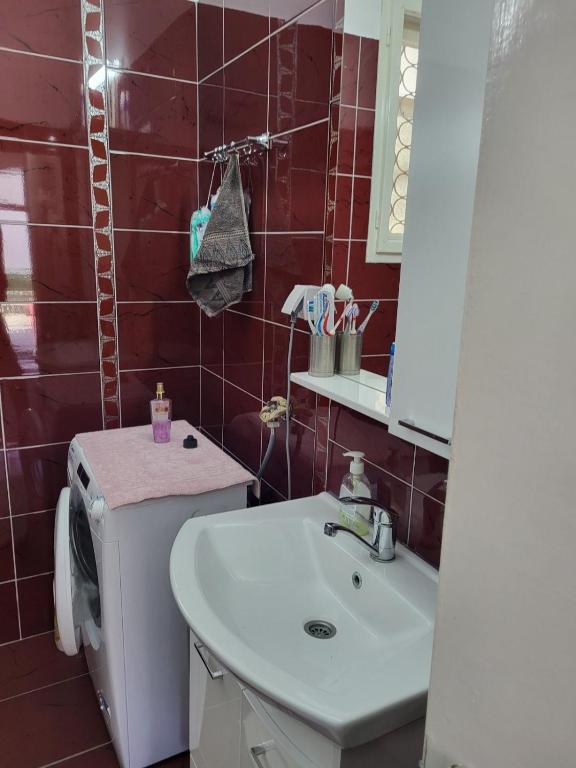 uma casa de banho com um lavatório e uma parede de azulejos vermelhos em Zelena Oaza em Jagodina