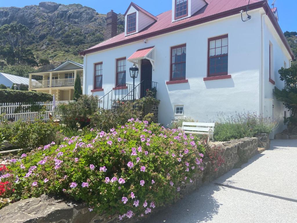 a white house with flowers in front of it at Poet's Cottage Stanley in Stanley