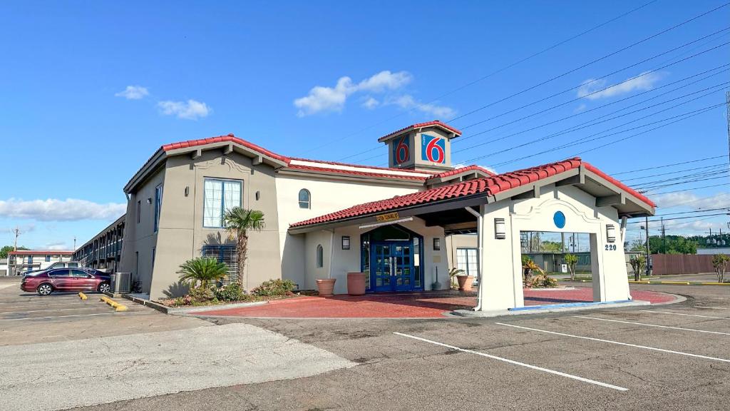 Un edificio con una torre de reloj en un estacionamiento. en Motel 6-Beaumont, TX, en Beaumont