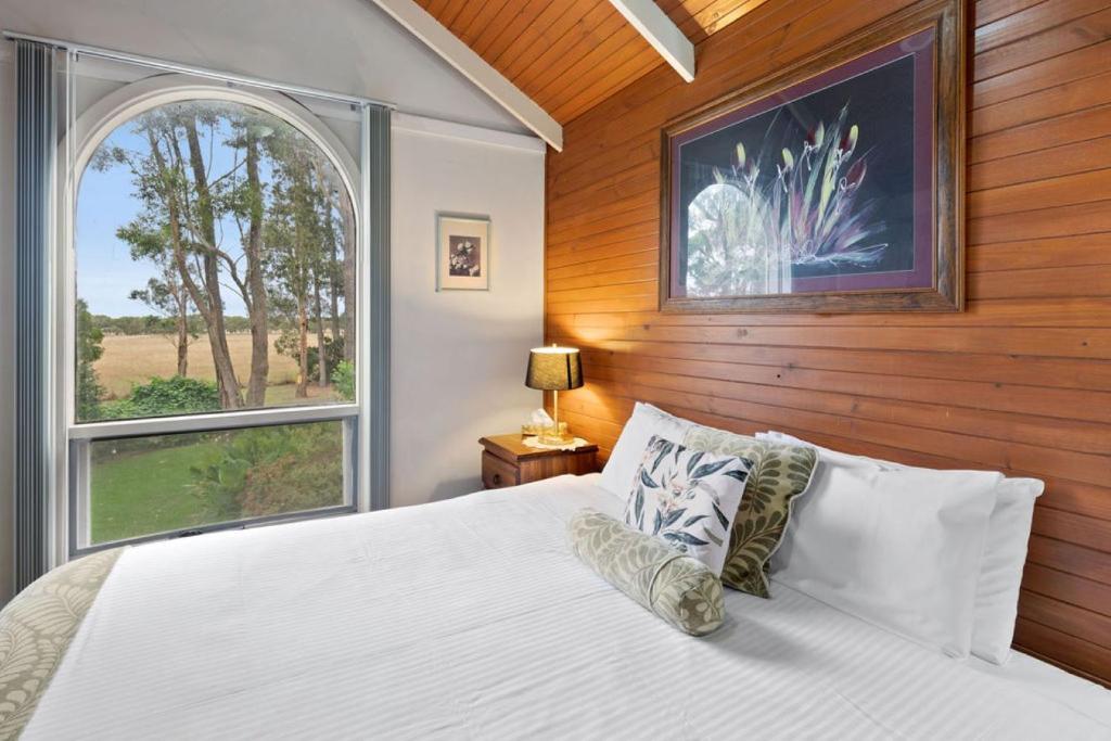 a bedroom with a white bed and a window at Clarendon Chalets in Mount Gambier