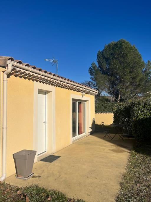 une maison jaune avec une poubelle devant elle dans l'établissement Gîte en Drôme Provençale, à Espeluche