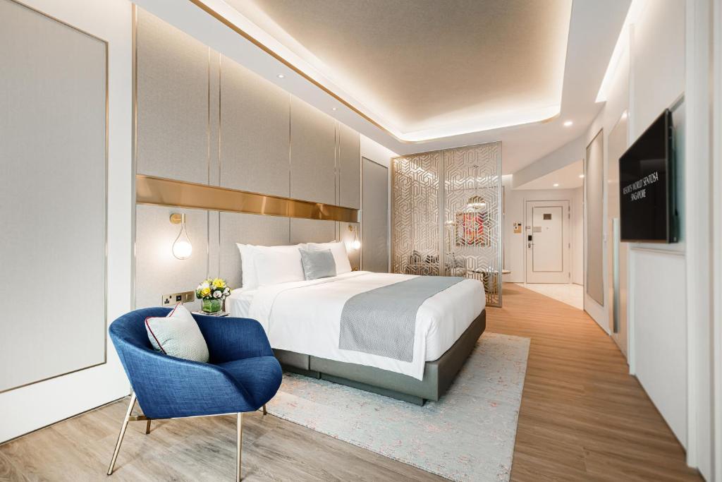 une chambre d'hôtel avec un lit et une chaise bleue dans l'établissement Resorts World Sentosa - Crockfords Tower, à Singapour