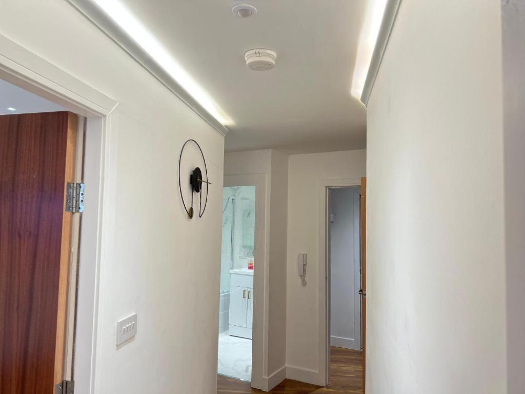 un pasillo con una pared blanca y un reloj en el techo en Manhattan Luxury Suites, en Bradford