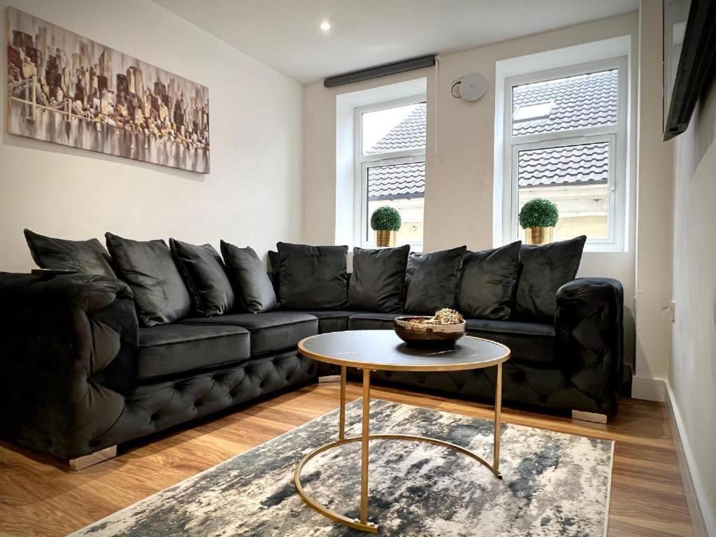 uma sala de estar com um sofá preto e uma mesa em Manhattan Luxury Suites em Bradford