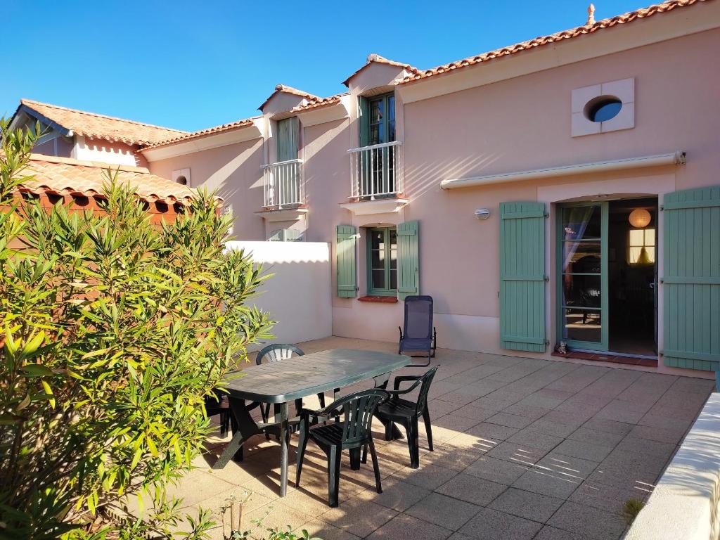 un patio avec une table et des chaises devant une maison dans l'établissement Maison avec piscine chauffée, à 500m de la plage et proche forêt - Terrasse, vélos inclus - FR-1-652-3, à Saint-Hilaire-de-Riez