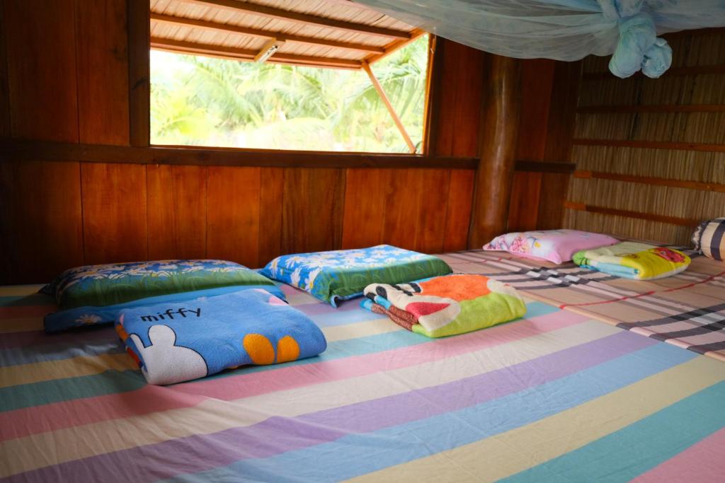 grupa poduszek na łóżku w pokoju w obiekcie Farmstay Sokfarm w mieście Trà Vinh
