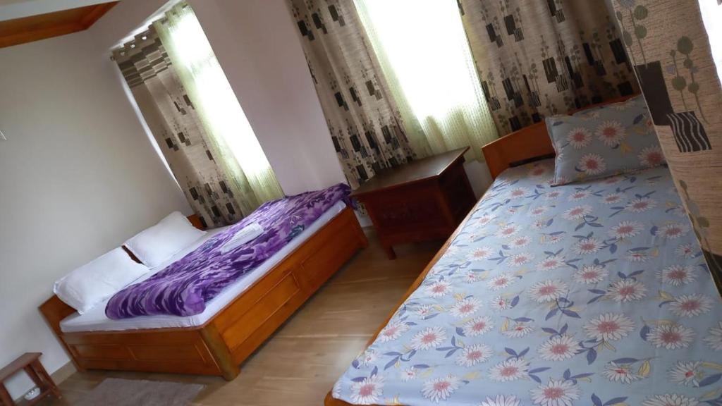 a bedroom with two beds and two windows at Coral Homestay in Pelling