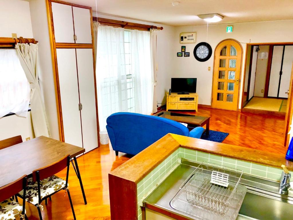 uma sala de estar com uma mesa e uma cadeira azul em ゲストハウス奄美ルリカケス em Amami