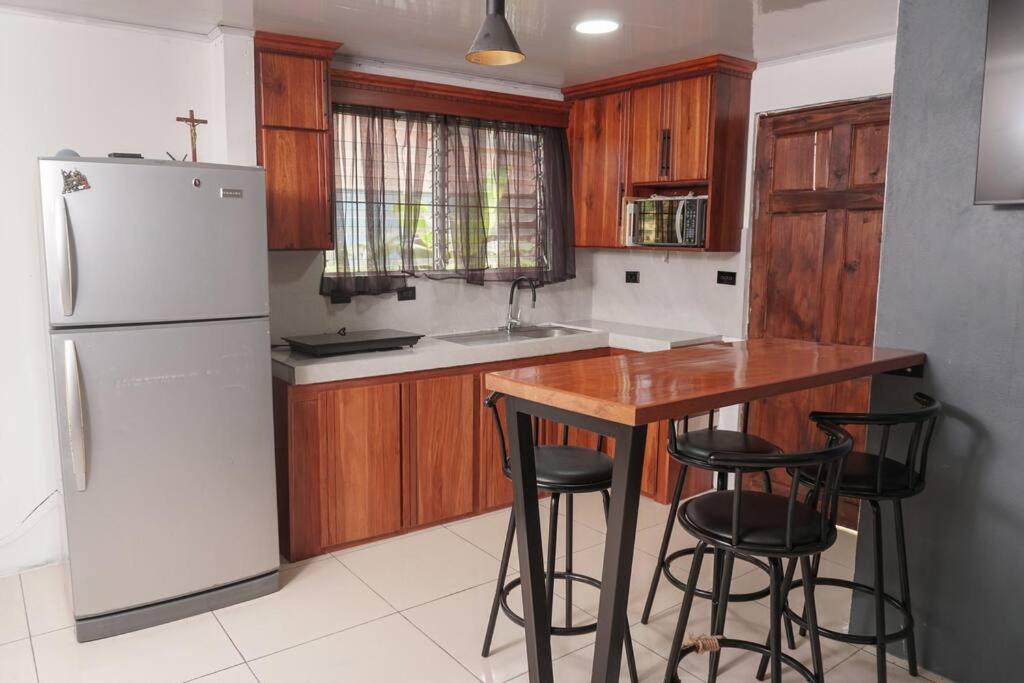 a kitchen with a white refrigerator and a table and stools at Nalu Home in San Francisco de Palmera