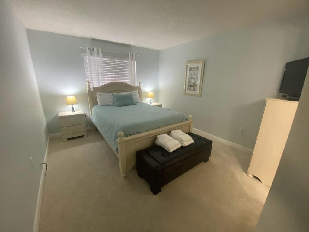 a small bedroom with a bed and a ottoman at Seaside Sanctuary Condo Villa - Private Beach Access, 3 Pools in Hilton Head Island