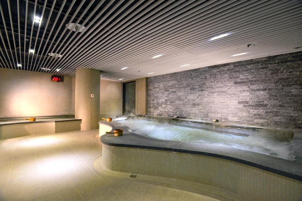 a large bath tub in a room with a brick wall at The Gaia Hotel - Taipei in Taipei