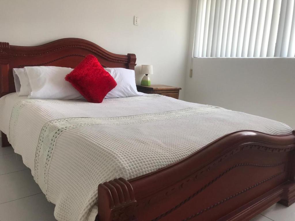 ein Bett mit zwei roten Kissen darüber in der Unterkunft Apartamento Dúplex - Barrio Maldonado Tunja in Tunja