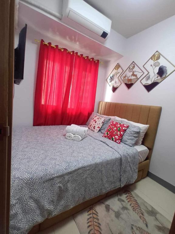 a bedroom with a bed with a red curtain at Staycation Near MOA by Cozypura with Pay Parking at S Res MOA in Manila