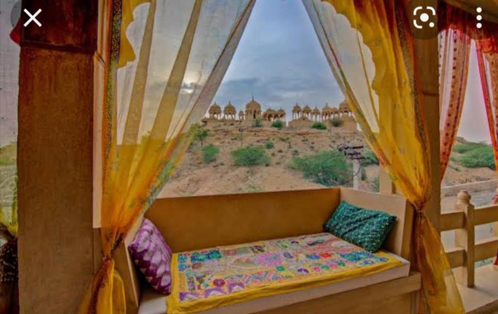 a couch in a room with a view of a desert at Desert Golden Palace in Jaisalmer