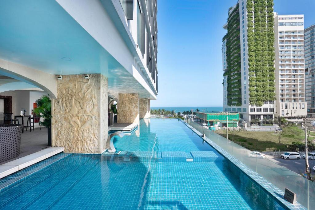 A rooftop pool runs beside the hotel with a glimpse of the sea beyond the city.