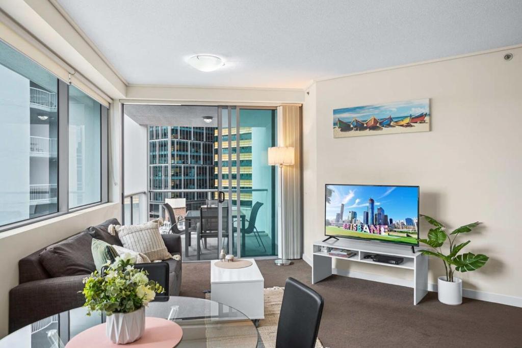 a living room with a couch and a tv at Cosy 1-Bed Unit with a Gym, BBQ Area, Spa and Pool in Brisbane