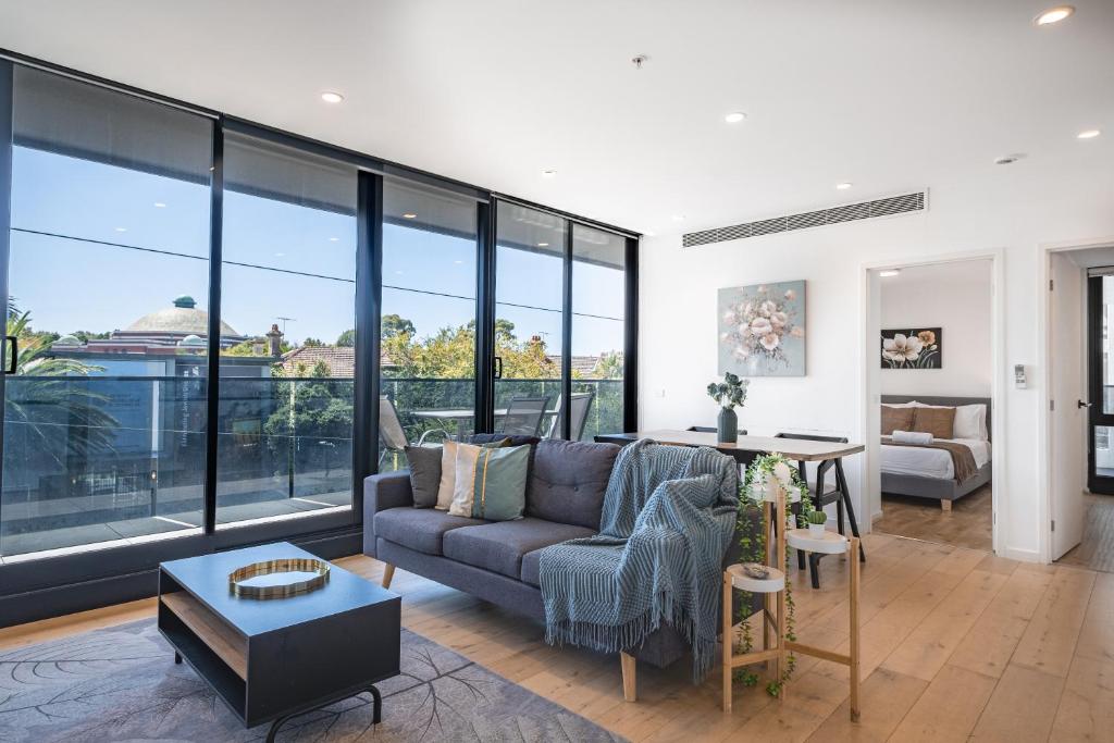 uma sala de estar com um sofá e janelas grandes em Modern 2br Apartment With Free Carpark And Pool em Melbourne