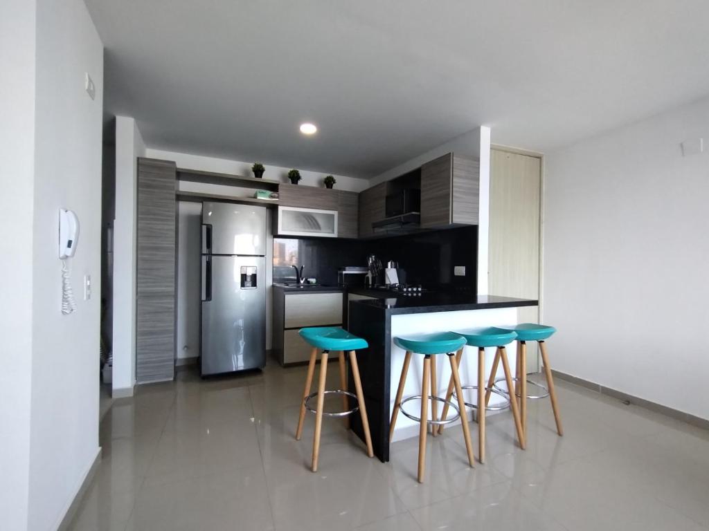 cocina con barra con 3 taburetes y nevera en Acogedor apartamento en exclusivo barrio de Barranquilla, en Barranquilla