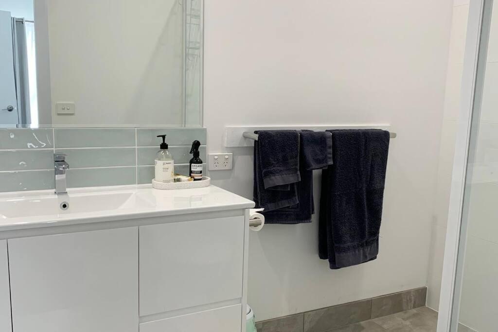 La salle de bains blanche est pourvue d'un lavabo et d'un miroir. dans l'établissement Family home central to everything, à Mildura
