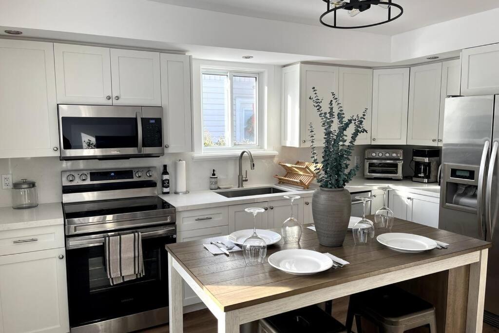 a kitchen with white cabinets and a wooden table at New and Cozy Cottage Minutes to Blue Mountain in Meaford