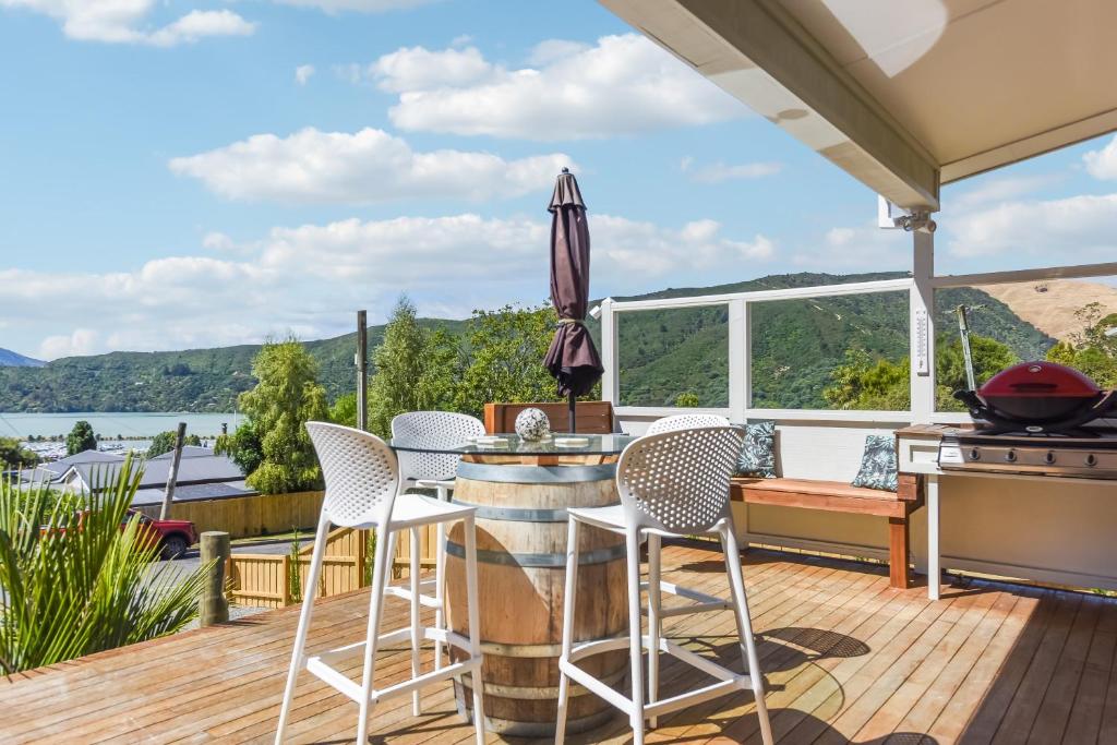 una terrazza con tavolo, sedie e griglia di Vista Del Porto - Havelock Holiday Home a Havelock