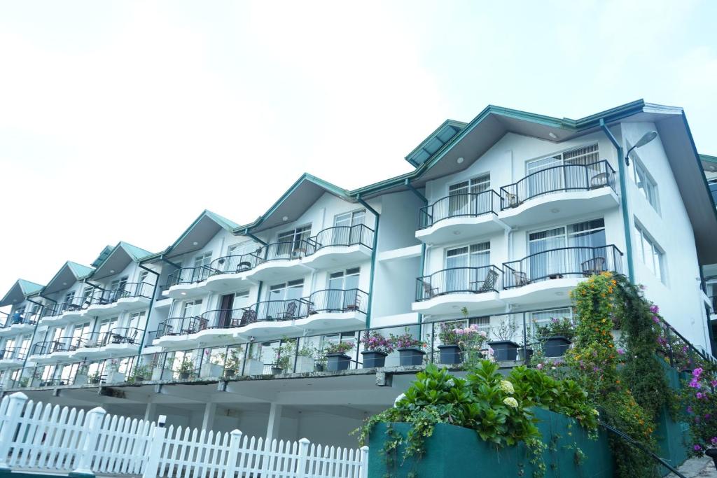 a large white building with balconies and flowers at Lake infinity Penthouse in Nuwara Eliya