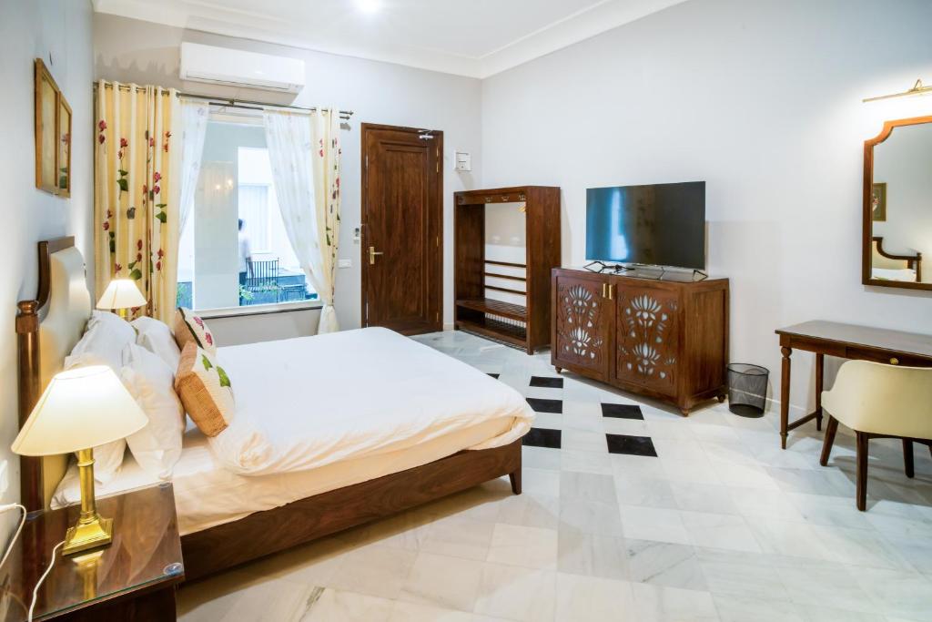 sypialnia z łóżkiem, biurkiem i telewizorem w obiekcie Chez Lavania - A Boutique Homestay w mieście Udaipur