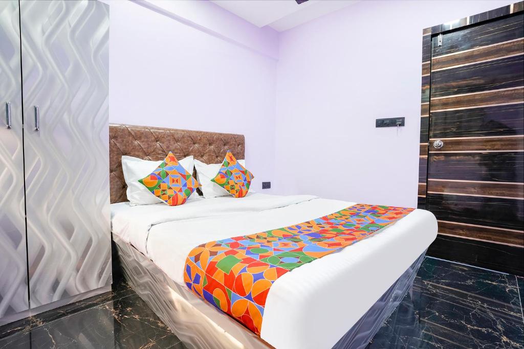 1 dormitorio con 1 cama con sábanas y almohadas coloridas en FabExpress Kirtiraj, en Panvel