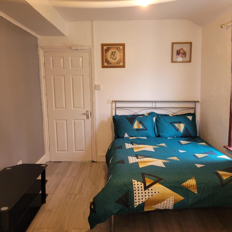 a bedroom with a bed with a blue comforter at A room self contain in Plumstead
