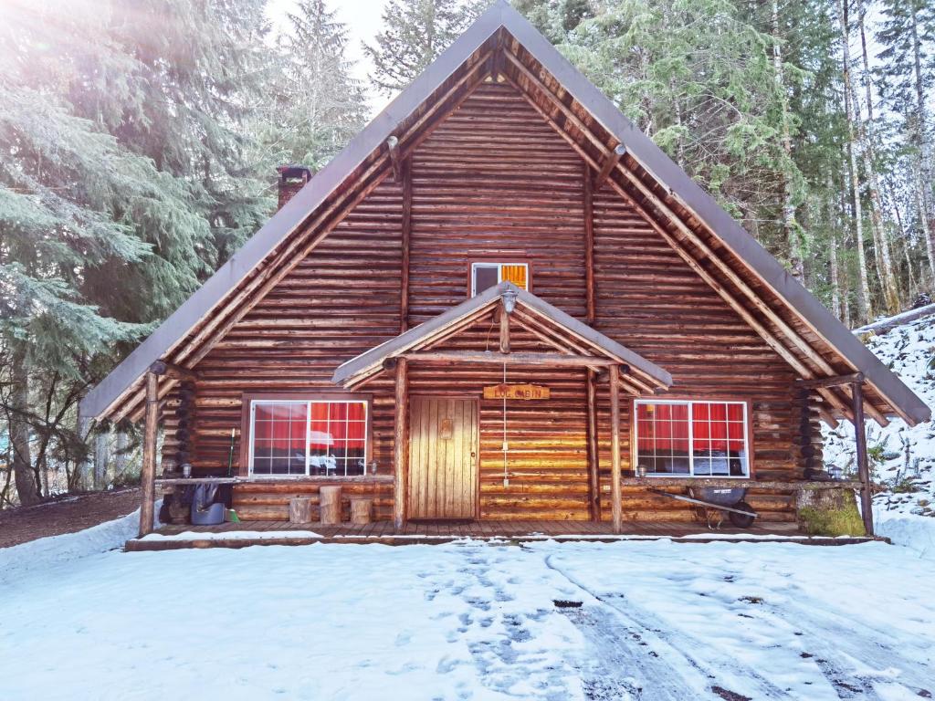 uma cabana de madeira na floresta na neve em Log Cabin at Rainier Lodge (0.4 miles from entrance) em Ashford