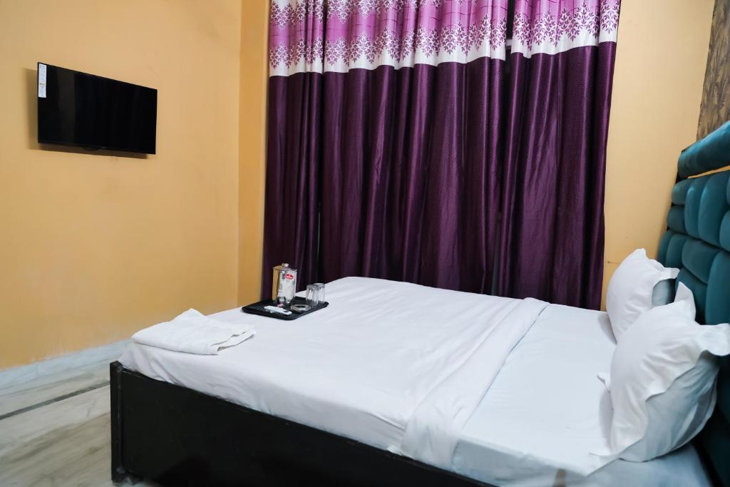 1 dormitorio con cama y cortina púrpura en Roomshala 126 Mannat Inn Laxmi Nagar, en Nueva Delhi