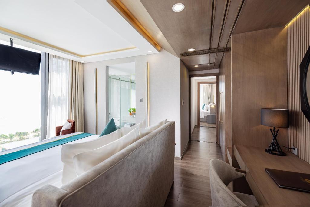 A compact sitting and work area beside a bed, with a narrow desk and a long corridor toward the bathroom.
