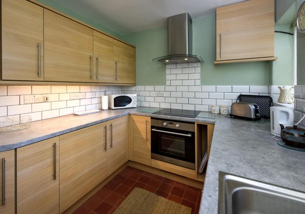 a kitchen with wooden cabinets and a stove top oven at Dolwar in Abersoch
