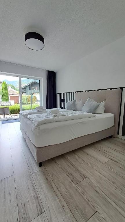 a white bedroom with a large bed and a wooden floor at Apartment Kampenwand in Aschau im Chiemgau