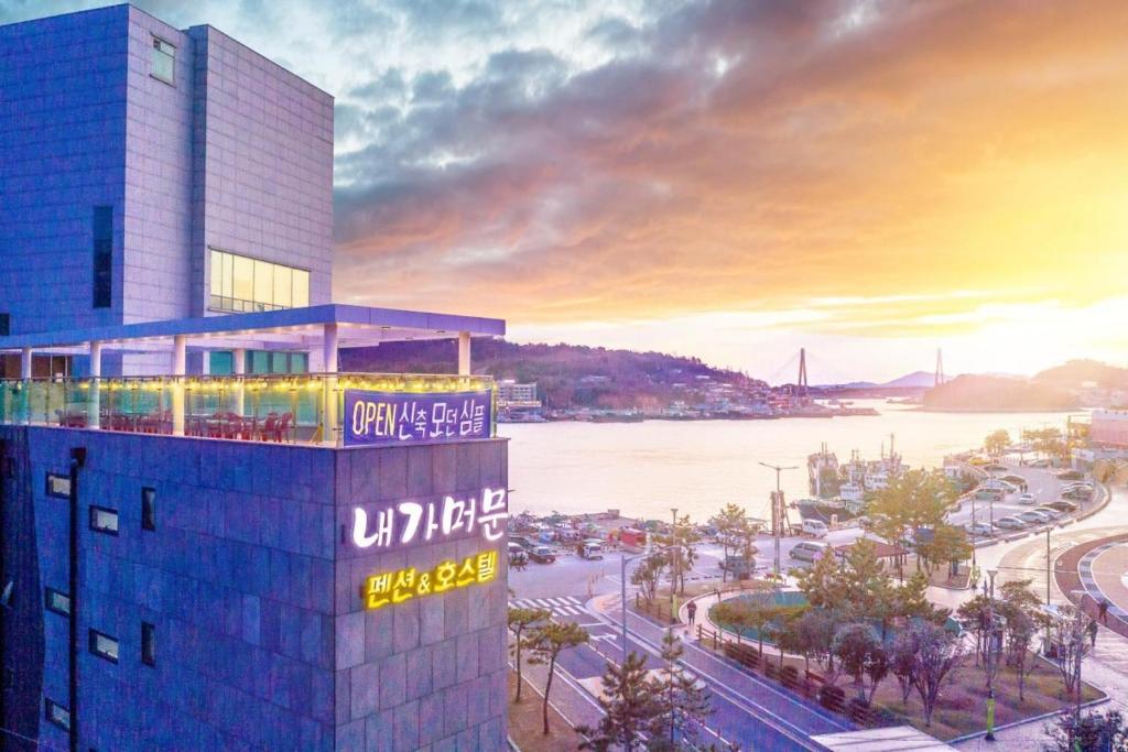 una representación de un edificio con una puesta de sol en el fondo en Yeosu My Stay Pension, en Yeosu