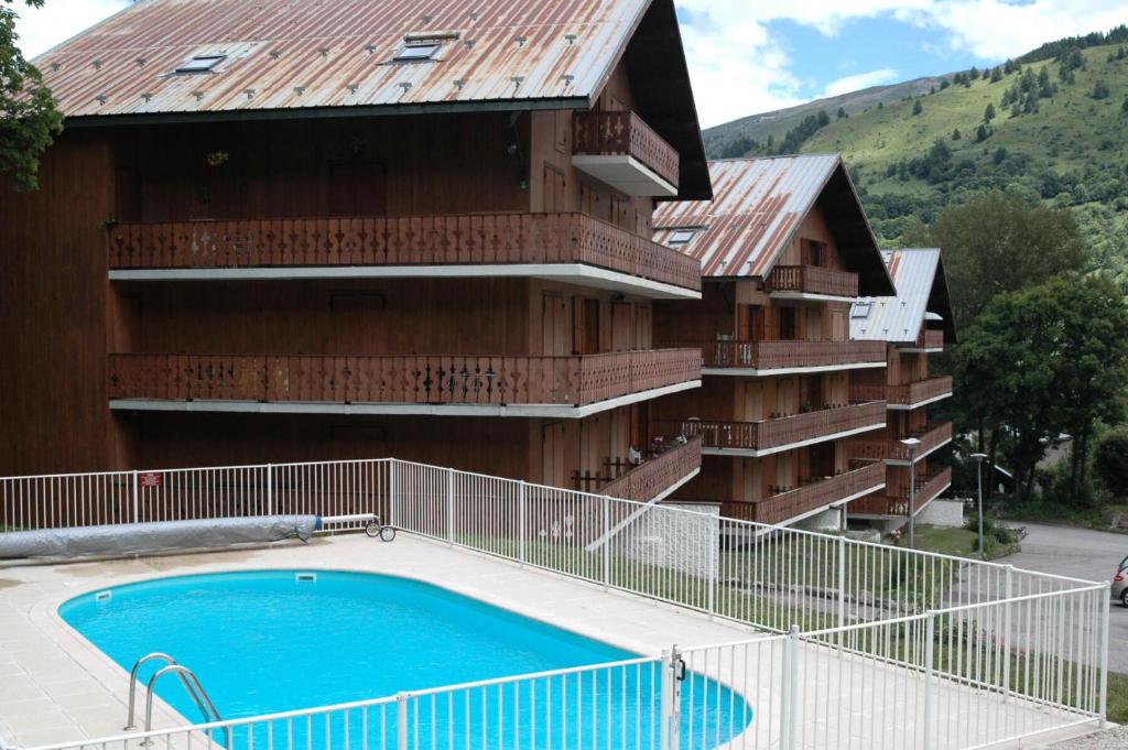 a building with a swimming pool in front of it at Résidence Les Arolles - 2 Pièces pour 6 Personnes 24 in Valloire