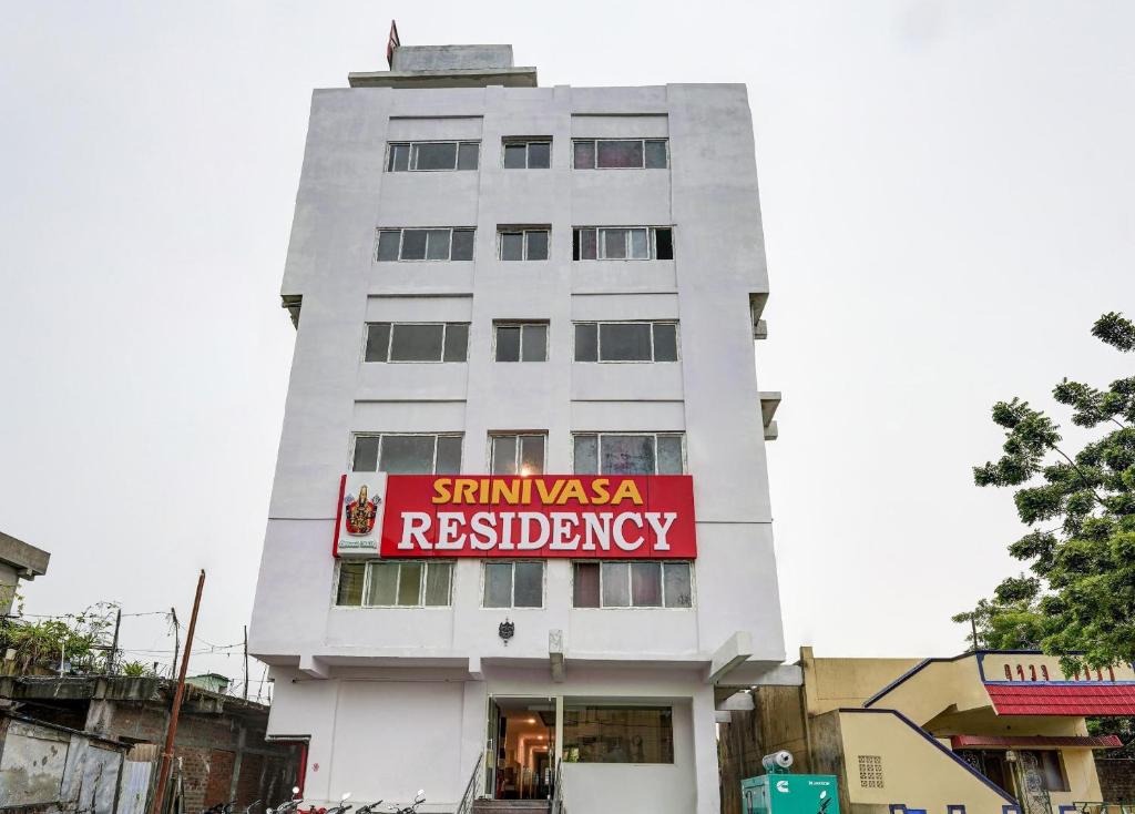 un grand bâtiment blanc avec un panneau rouge sur lui dans l'établissement Collection O Hotel Srinivasa Residency, à Tirupati