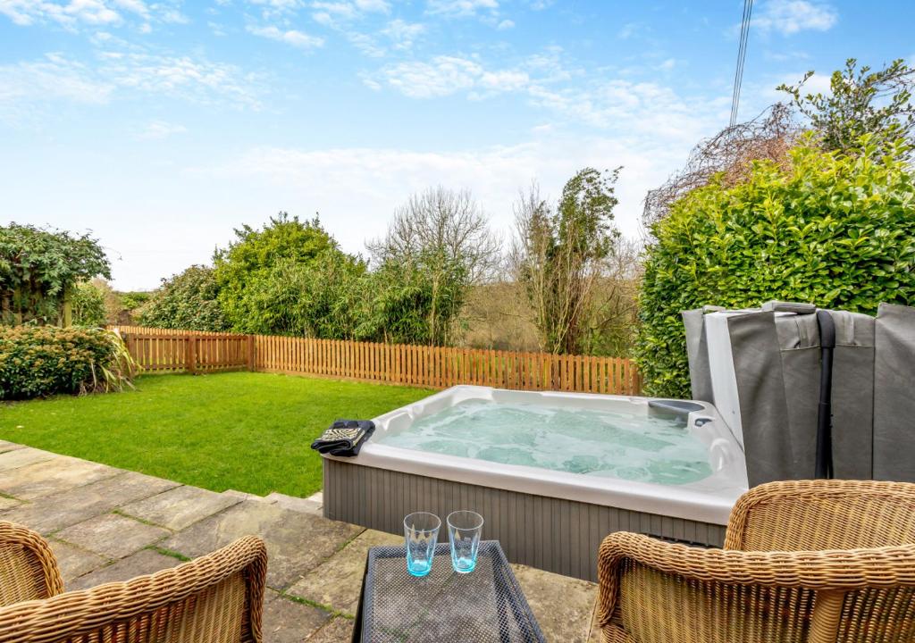 a hot tub in a backyard with chairs and a table at Oriel Cottage in Bittadon